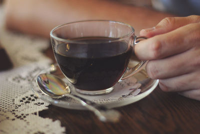 Close-up of hand holding coffee cup on table