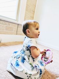 Cute baby girl in floral dress playing at home