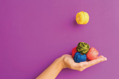 Colorful embroidery threads in hand on a purple background