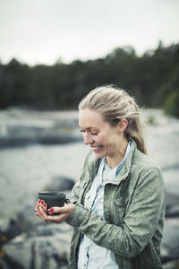 Happy wonderlust woman holding coffee mug outdoors