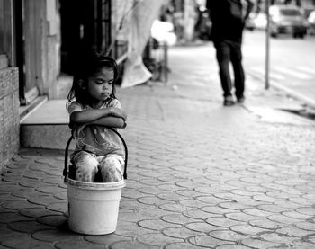 Girl relaxing in bucket on sidewalk