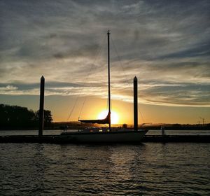 Silhouette of bridge over calm sea at sunset