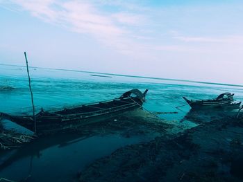 Fishing boat moored on sea against sky