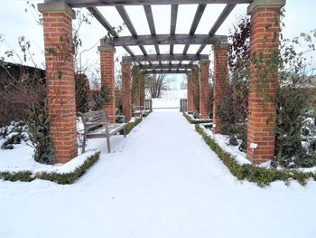 Snow covered footpath amidst buildings during winter