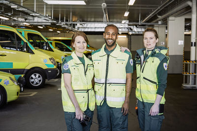 Portrait of male and female ambulance staff standing together in parking lot