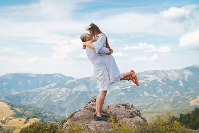 Man carrying woman while standing on mountain