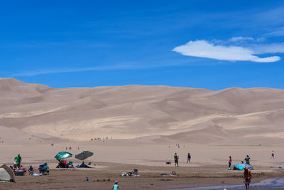 People enjoying in desert against sky