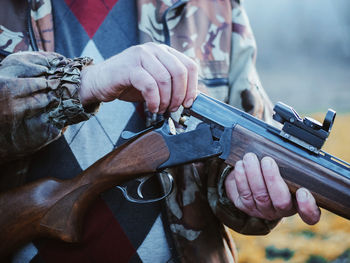 Midsection of army soldier holding rifle