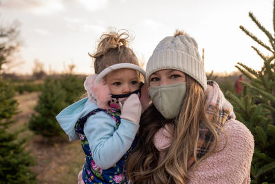 Portrait of mother with daughter wearing mask standing at field