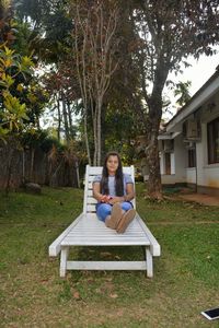 Young woman sitting on grass against trees