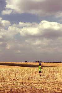 Rear view of man walking on field against sky