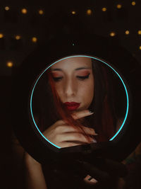 Portrait of young woman with illuminated string lights