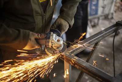 Midsection of man cutting metal