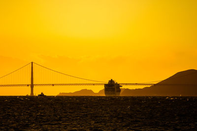 Silhouette of suspension bridge against sky during sunset