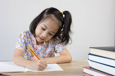 Girl drawing on book at home