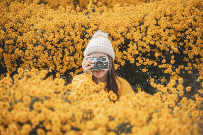 Portrait of woman standing amidst yellow flowering plants
