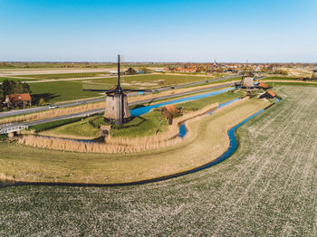 High angle view of agricultural field and windmills against clear sky