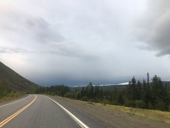 Road by trees against sky