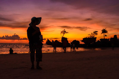 Silhouette people on beach against sky during sunset