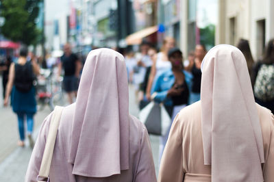 Rear view of nuns walking on street in city