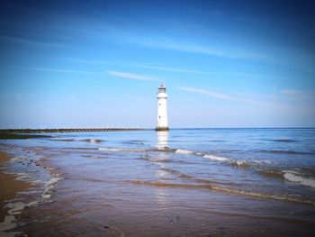 Lighthouse by sea against sky