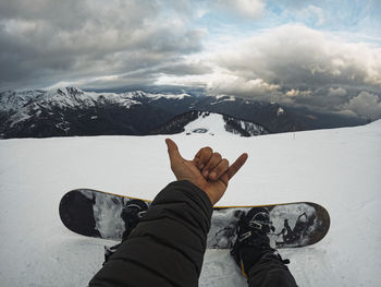 Low section of person on snow covered mountain against sky