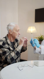 Cropped hand of doctor giving mask to senior man