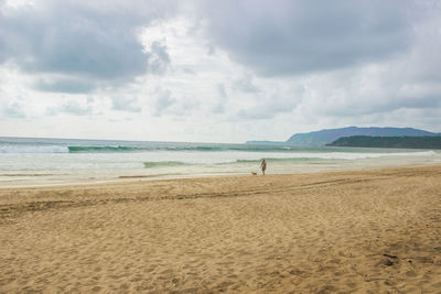 Scenic view of beach against cloudy sky