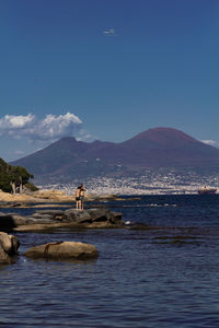 Scenic view of sea and mountains against blue sky