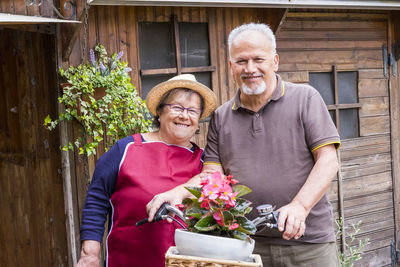 Portrait of smiling senior couple standing by house