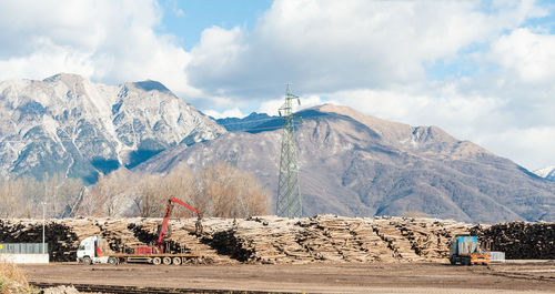 Stacked logs on field against mountains
