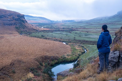 Rear view of man looking at lake against mountain