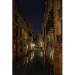 Canal amidst buildings against clear sky at night