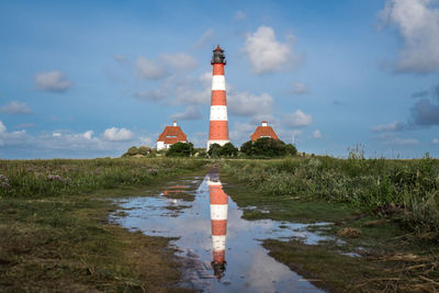 Lighthouse by sea against sky