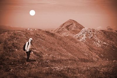 Person standing by mountains against sky