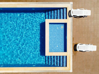 Sunbeds near the swimming pool top down view.