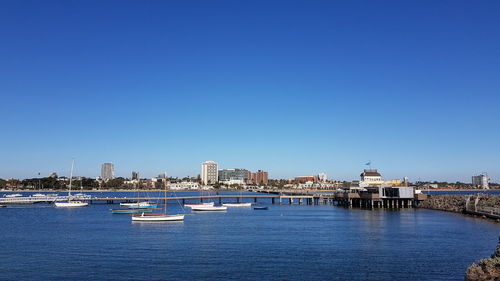 Scenic view of river by buildings against clear blue sky