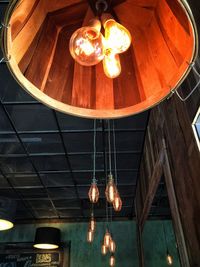 Low angle view of illuminated light bulb hanging on ceiling