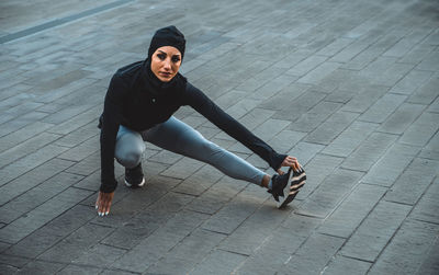 High angle view of young woman sitting on footpath