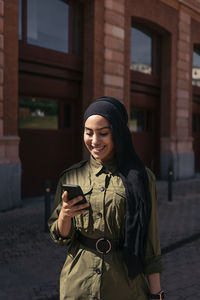 Young woman standing against building