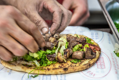 Close-up of person preparing food in plate on table