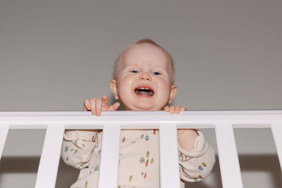 Portrait of cute baby boy sitting on wooden wall