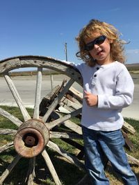 Portrait of boy wearing sunglasses while standing with wheel at roadside