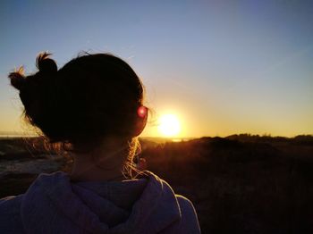 Close-up of girl on field against sky during sunset