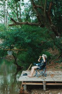 Young woman sitting by plants in forest