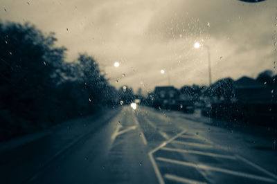 Road seen through wet glass window in rainy season