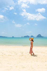 Woman standing at beach against sky