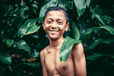 Portrait of smiling young man standing amidst leaves