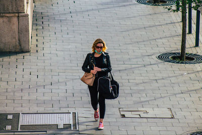 Full length of woman on footpath against brick wall