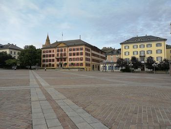 Street by buildings in town against sky